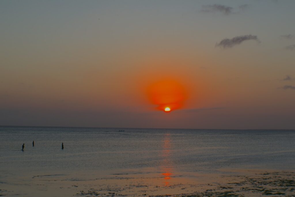 zanzibar-tramonto Tramonto infuocato sulla costa Ovest di Zanzibar, mentre le donne locali rientrano dalla pesca